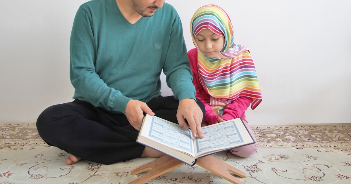 An adult reading a book together with a young child